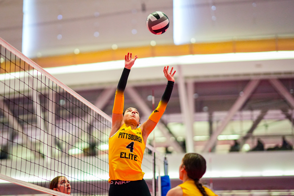 Camdynn midair reaching for the volleyball to set to her teammate